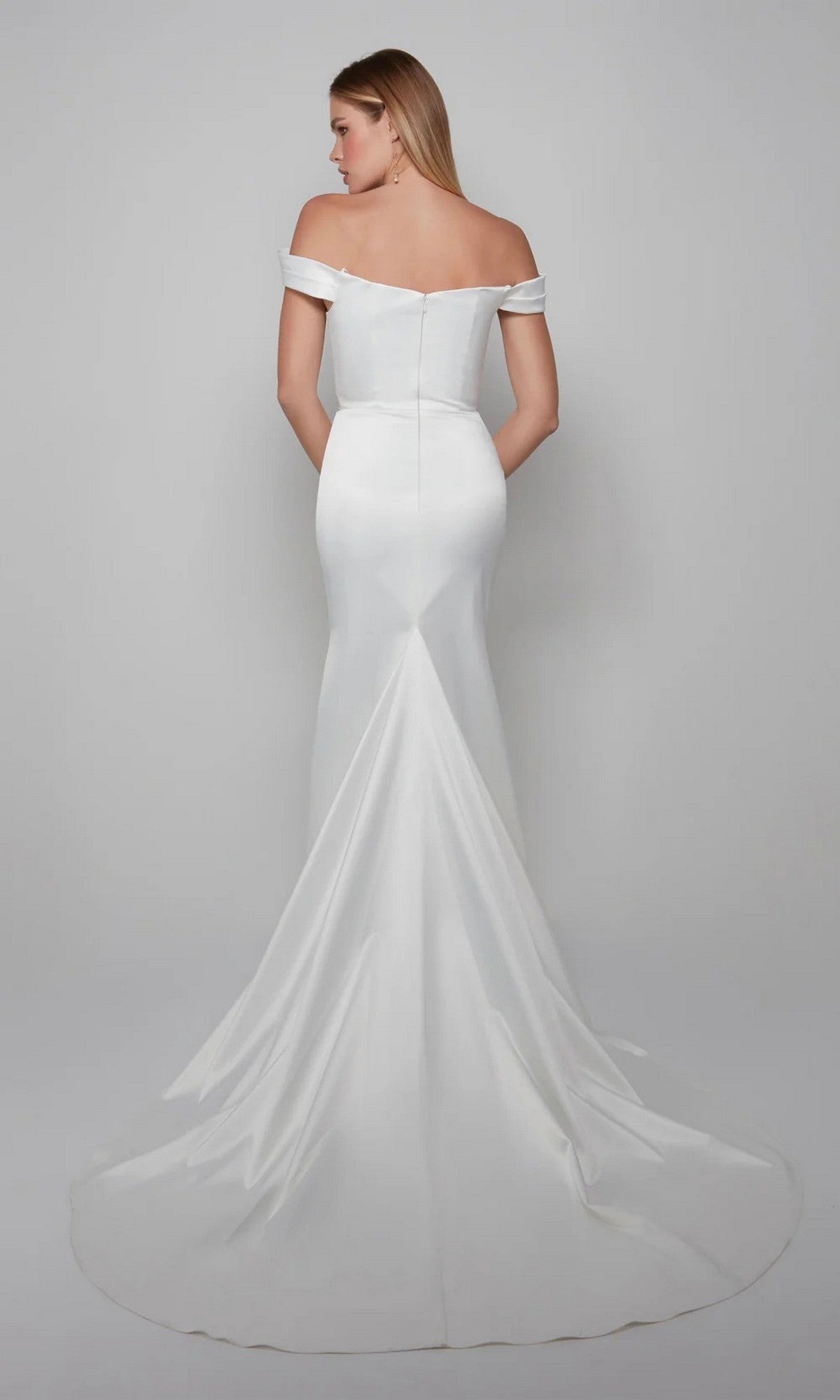A woman is photographed from the back in the Alyce 7064 Long White Dress, a fitted off-the-shoulder gown with a long train, set against a plain light gray background.